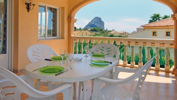A balcony with a table set for dining, overlooking a mountainous landscape. - Villa Senieta - PlusHolidays (Calpe)