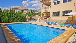 A swimming pool with lounge chairs and a building with a balcony. - Villa Senieta - PlusHolidays (Calpe)