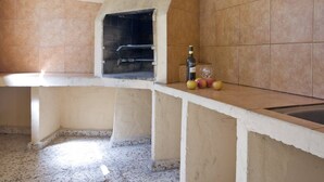 A kitchen with a built-in oven, a wine bottle, and some fruit on the counter. - Villa Senieta - PlusHolidays (Calpe)