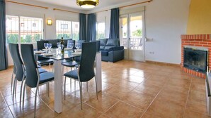 A spacious living area with a dining table, chairs, a sofa, and a fireplace. - Villa Senieta - PlusHolidays (Calpe)