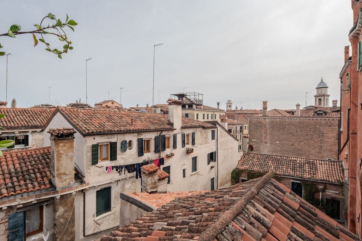 A view of terracotta-tiled rooftops in a densely built urban area with buildings of varying heights and architectural styles.