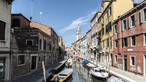 A narrow canal flanked by historic buildings with a tower in the distance.