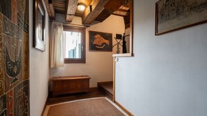 A narrow hallway with a wooden bench, a framed artwork on the wall, and a patterned floor.