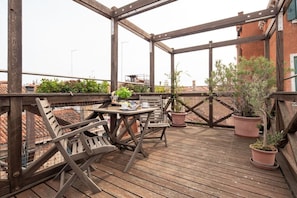 Une terrasse en bois avec une table et des chaises, entourée de plantes en pot.