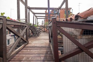 A wooden pedestrian bridge with metal railings and a metal staircase. - Altana studio (Venezia)
