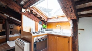 A compact kitchen with a gas stove, oven, and sink, wooden cabinets, and a skylight.