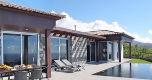 Una villa moderna con piscina, pareti in pietra e ampie vetrate.