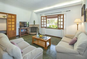 Una sala de estar con un sofá, una mesa de centro, un televisor, una estantería y una chimenea.