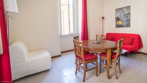A dining area with a round wooden table, four wooden chairs, a white sofa, and a red-covered couch. - Holiday home "Vatican 2 steps" (Roma)