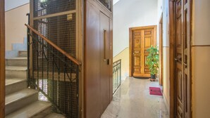 A staircase with metal railings, a wooden door, and a potted plant in a hallway. - Holiday home "Vatican 2 steps" (Roma)