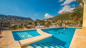 A swimming pool with a view of a town and mountains in the background. - Villa Encanto - PlusHolidays (Calpe)