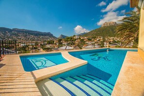 Piscina com vista para uma cidade e montanhas ao fundo.