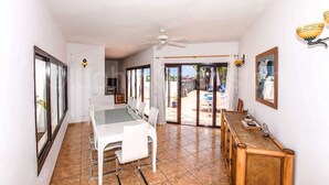 A dining area with a table and chairs, a ceiling fan, and a view through glass doors to an outdoor area.