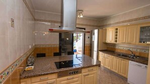 A kitchen with a central island, stainless steel appliances, and a tiled backsplash.