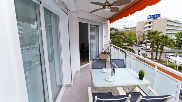 Een balkon met een tafel, stoelen en een plafondventilator.
