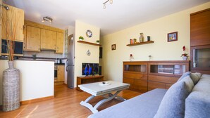 Um espaço de estar moderno com armários de madeira, cozinha e área de estar com sofá.