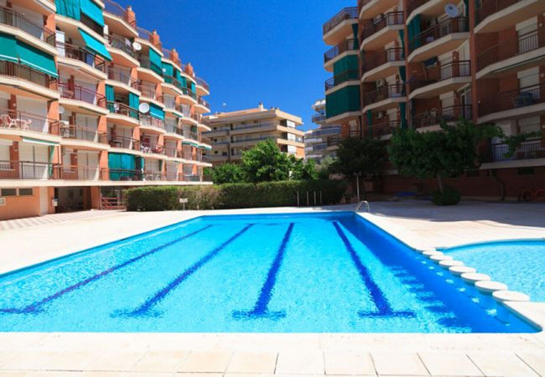 A swimming pool surrounded by multi-story residential buildings with balconies.
