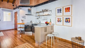 A modern kitchen with a central island, wooden flooring, and a brick ceiling.