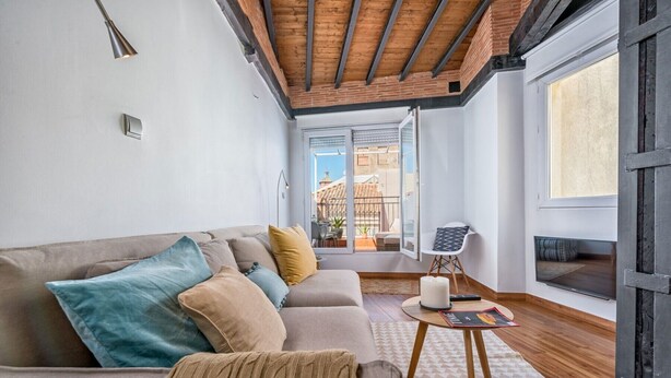 A modern living room with a sofa, a small table, and a view of the outside.