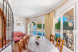 A balcony with a pool, a dining table with chairs, and a sofa. - Villa Cruz - PlusHolidays (Calpe)