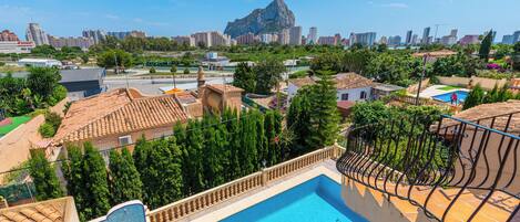 Zona residencial con piscina, tejados de teja terracota y vistas de un paisaje urbano con una montaña destacada al fondo.