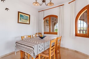 A dining area with a table set for four, surrounded by wooden chairs. - Villa Cruz - PlusHolidays (Calpe)