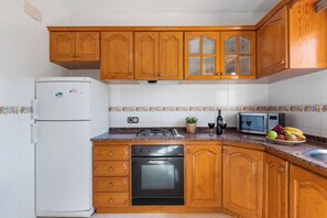 A kitchen with wooden cabinets, a white refrigerator, a stove, a microwave, and a sink.