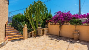 A stone staircase leading to a door, surrounded by cacti and bougainvillea. - Villa Cruz - PlusHolidays (Calpe)