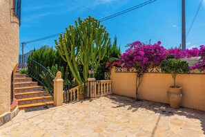 A stone staircase leading to a door, surrounded by cacti and bougainvillea. - Villa Cruz - PlusHolidays (Calpe)