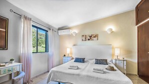 Ein Schlafzimmer mit einem großen Bett, zwei Nachttischen, einem Schreibtisch und einem Kleiderschrank.