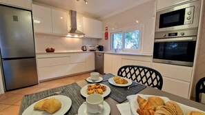 A modern kitchen with white cabinets, stainless steel appliances, and a dining area with breakfast items.