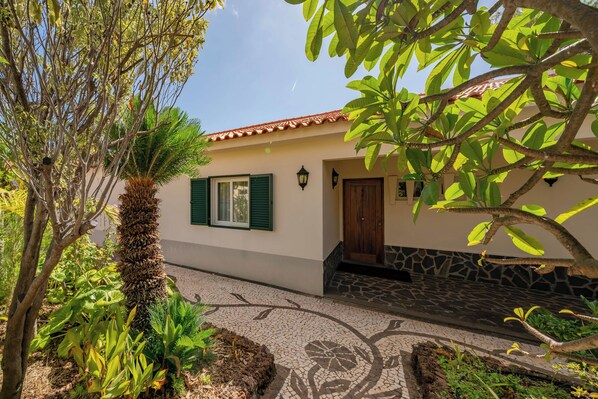 A house with a tiled roof, a door, and a window with shutters.