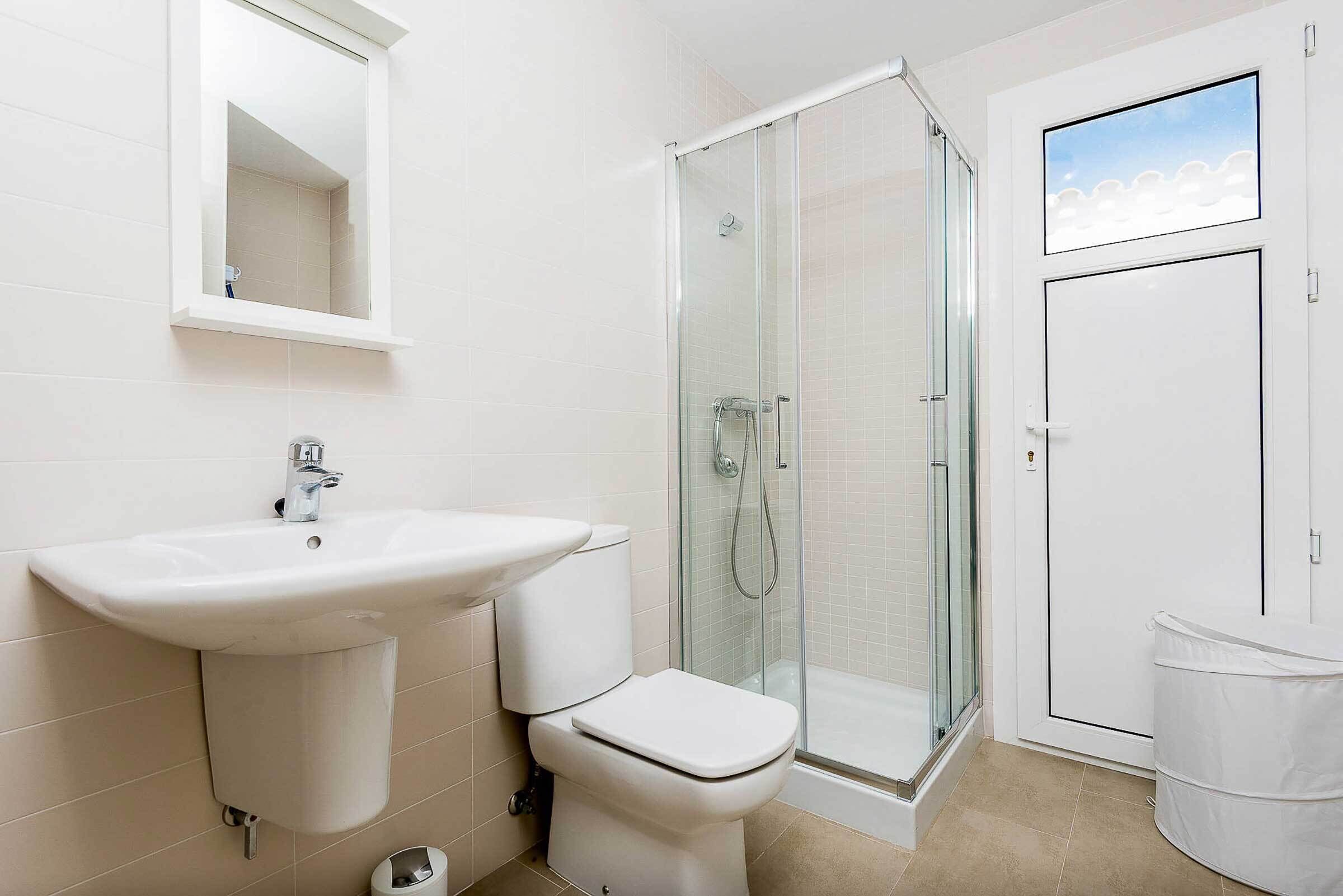 A bathroom with a sink, toilet, and glass-enclosed shower.