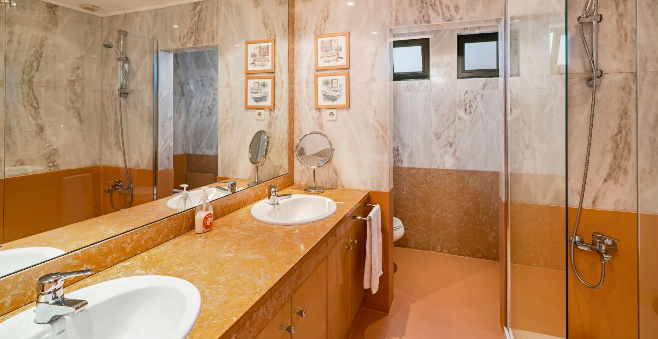 A bathroom with two sinks, a large mirror, and a shower area.