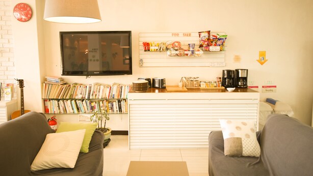 Una sala de estar con sofá, cafetera, televisor y estantería.