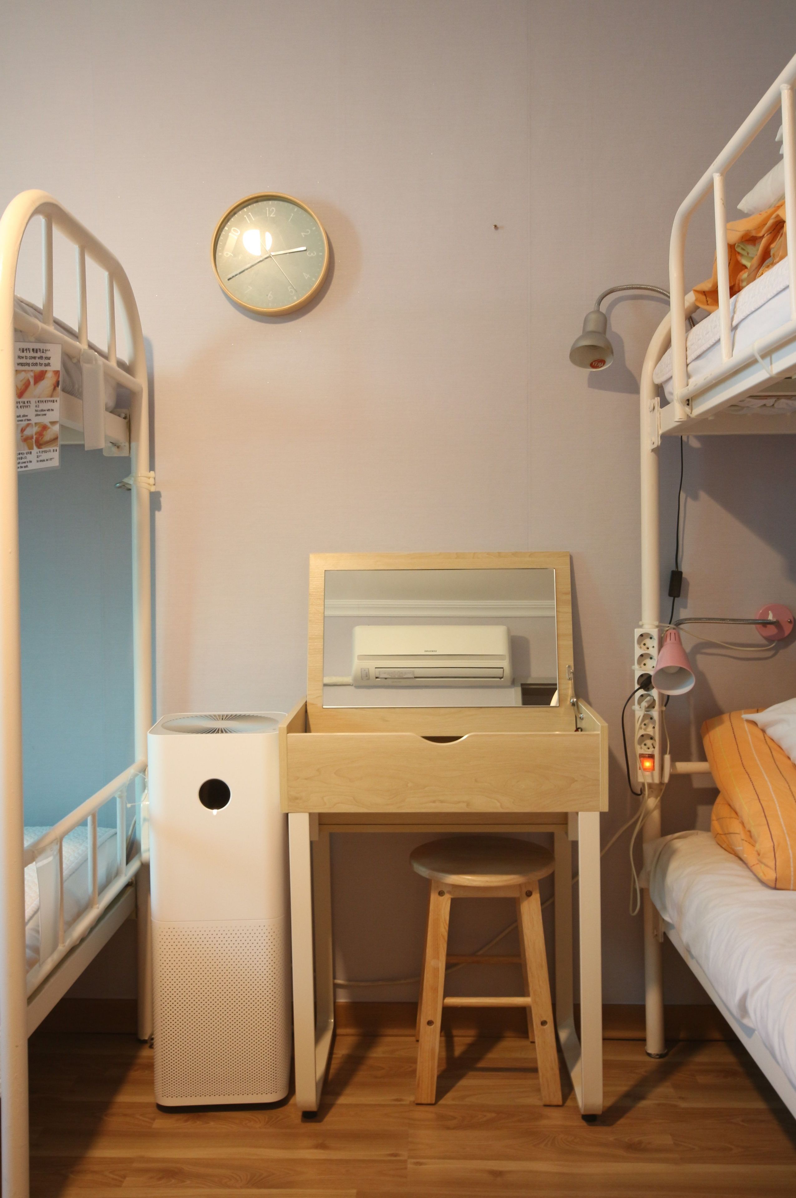 A child's bedroom with bunk beds, a desk with a chair, a clock, and a wastebasket.