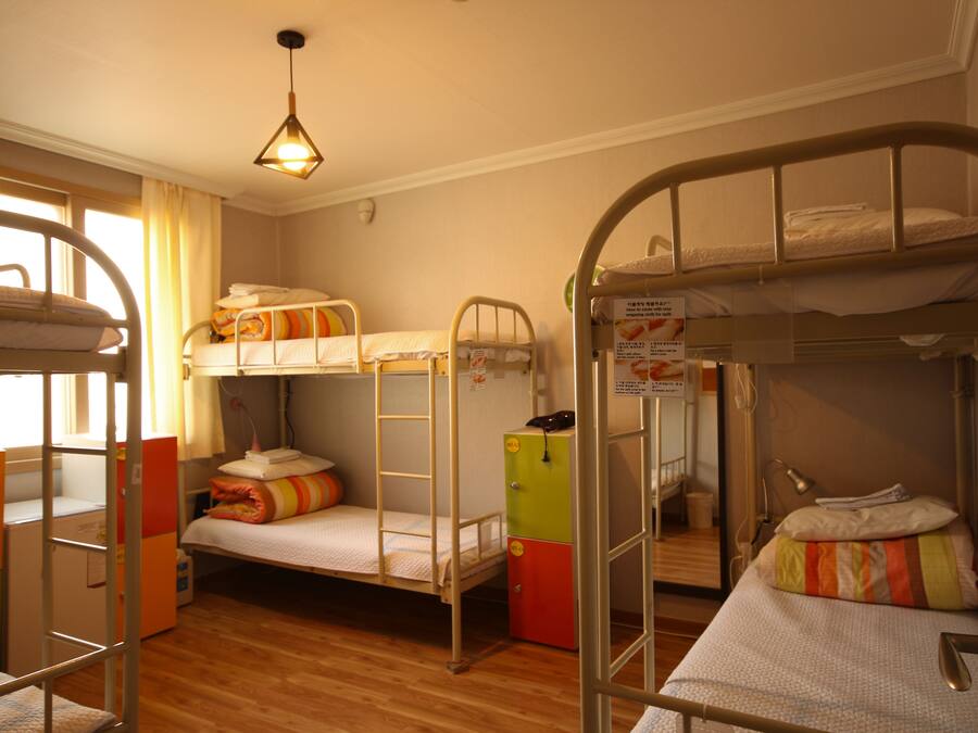 A bunk bed room with a wooden floor, a desk, and a chair.