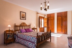 A bedroom with a wooden bed, bedside tables, a chandelier, and a large wardrobe.