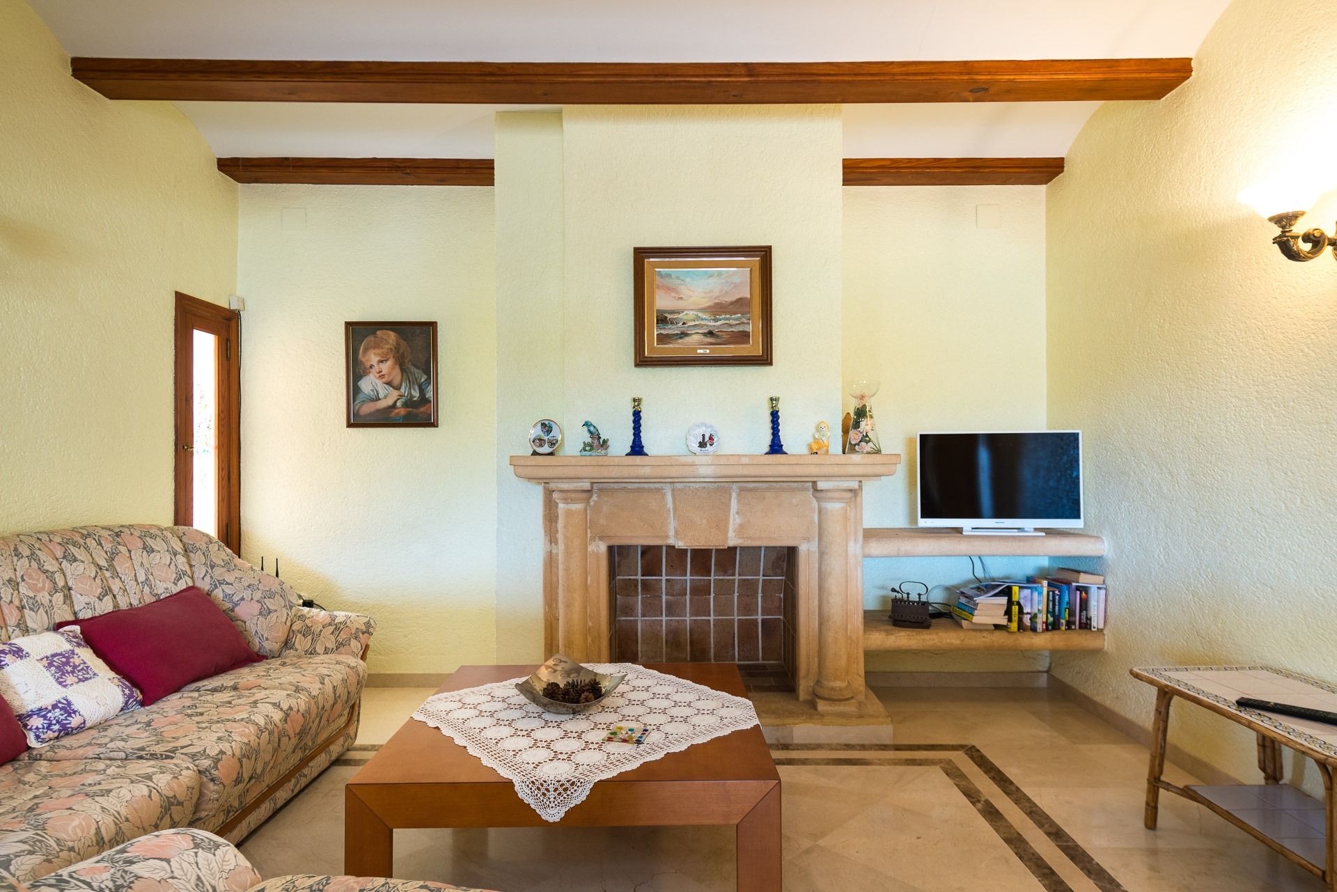 Ein Wohnzimmer mit Sofa, Couchtisch, Kamin, Fernseher und Bücherregal.