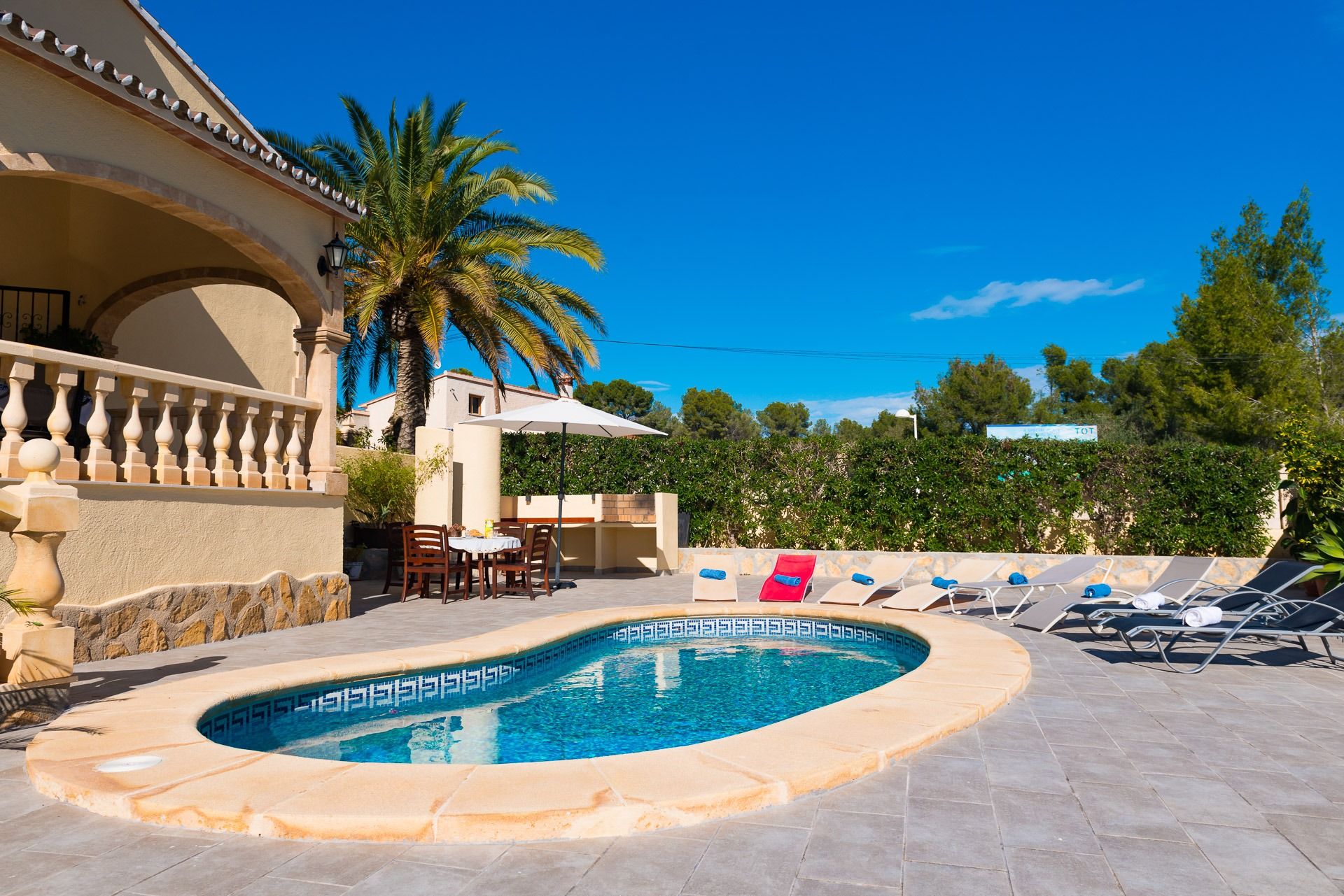 A swimming pool with a geometric tile design, surrounded by lounge chairs and a table with chairs.