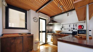 A modern kitchen with wooden cabinets, a stainless steel range hood, and a red kettle. - Rome, historic center, characteristic apartment for 6 (Roma)