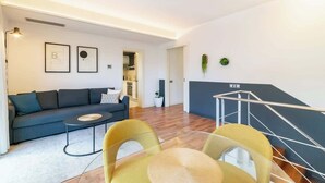 A modern living room with a sofa, coffee table, and chairs, a staircase, and framed artwork on the wall. - Central Penthouse with terrace Plaça Catalunya I (Barcelona)