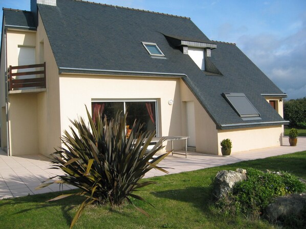 A modern house with a sloped roof, a balcony, and a large window.