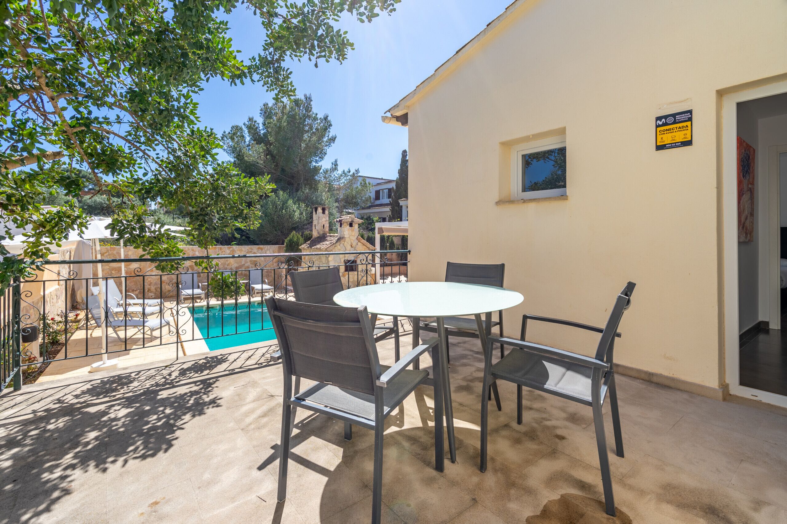 Un patio al aire libre con piscina, una mesa y sillas.