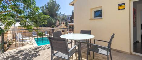Un patio al aire libre con piscina, una mesa y sillas.