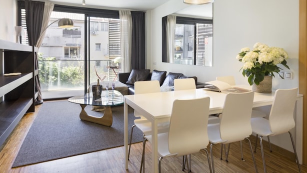 Un salon moderne avec un coin repas, de grandes fenêtres et une vue sur la ville.