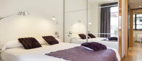 Ein modernes Hotelzimmer mit einem großen Bett, mehreren Nachttischlampen und einem großen Spiegel.