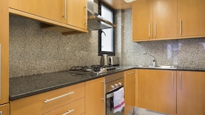 Une cuisine dotée de plans de travail en granit, de meubles en bois, d’un évier en acier inoxydable et d’une cuisinière à gaz.
