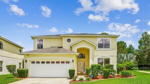 A two-story house with a garage, a front porch, and a well-maintained lawn.