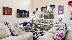 A living room with a sofa set, a flat-screen TV, a coffee table, and a patterned rug.